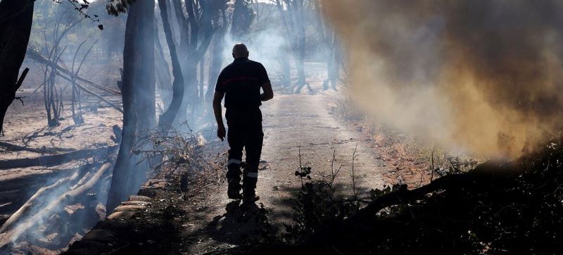 Un bombero camina por una zona llena de humo y árboles quemados tras un incendio forestal en Ille-sur-Tet, Francia.